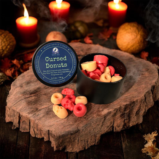Cursed Donuts packaging with donuts on a wooden surface with candles in the background