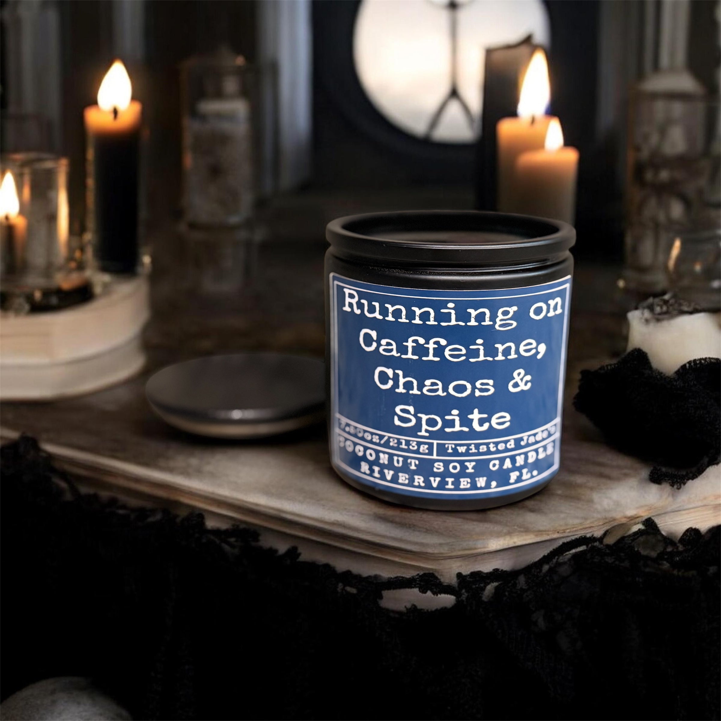 Candle with text 'Running on Caffeine, Chaos & Spite' on a dark background with candles.