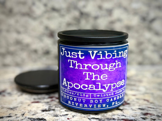 Twisted Jade's purple coconut soy candle with a humorous "Just Vibing Through The Apocalypse" label.